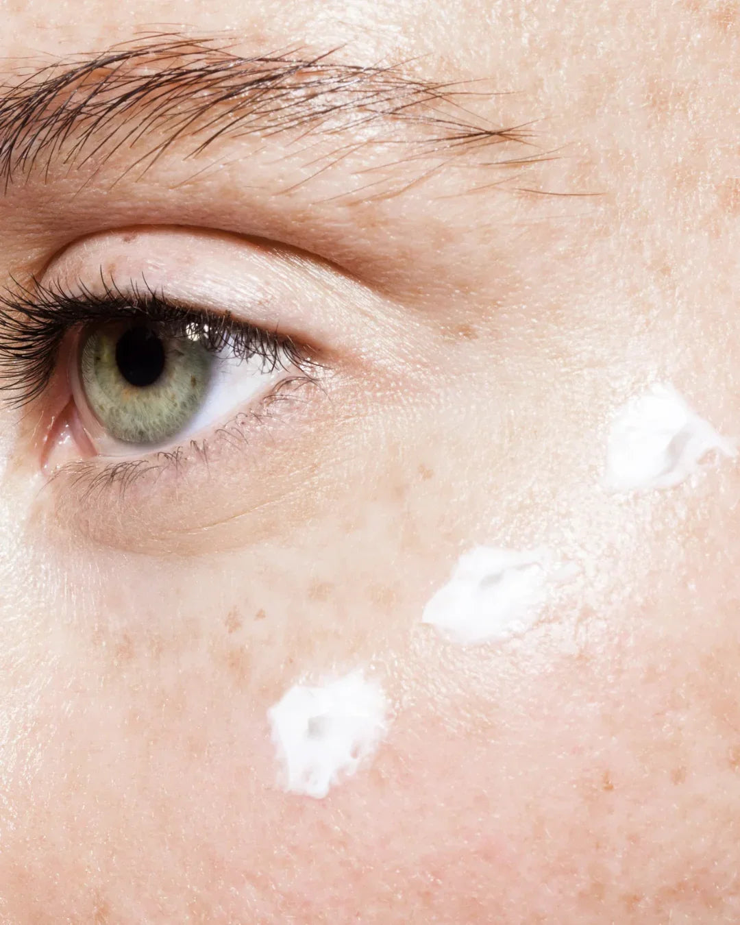 Dettaglio di una guancia con crema viso idratante BuzzSkin applicata sotto l’occhio