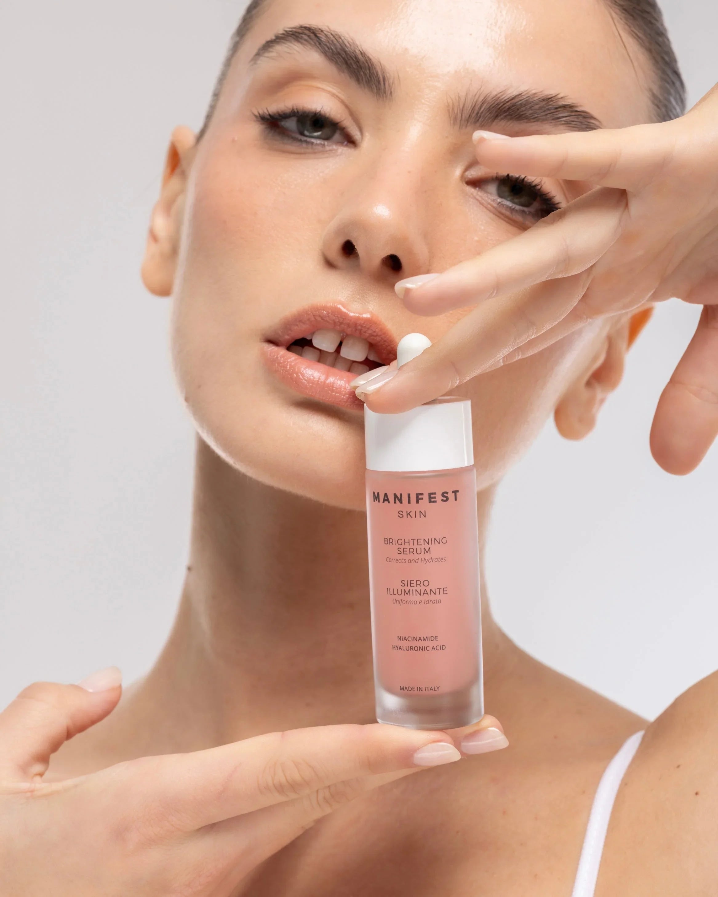 Donna con pelle luminosa tiene il siero illuminante Manifest Skin, skincare viso Buzz Skin.