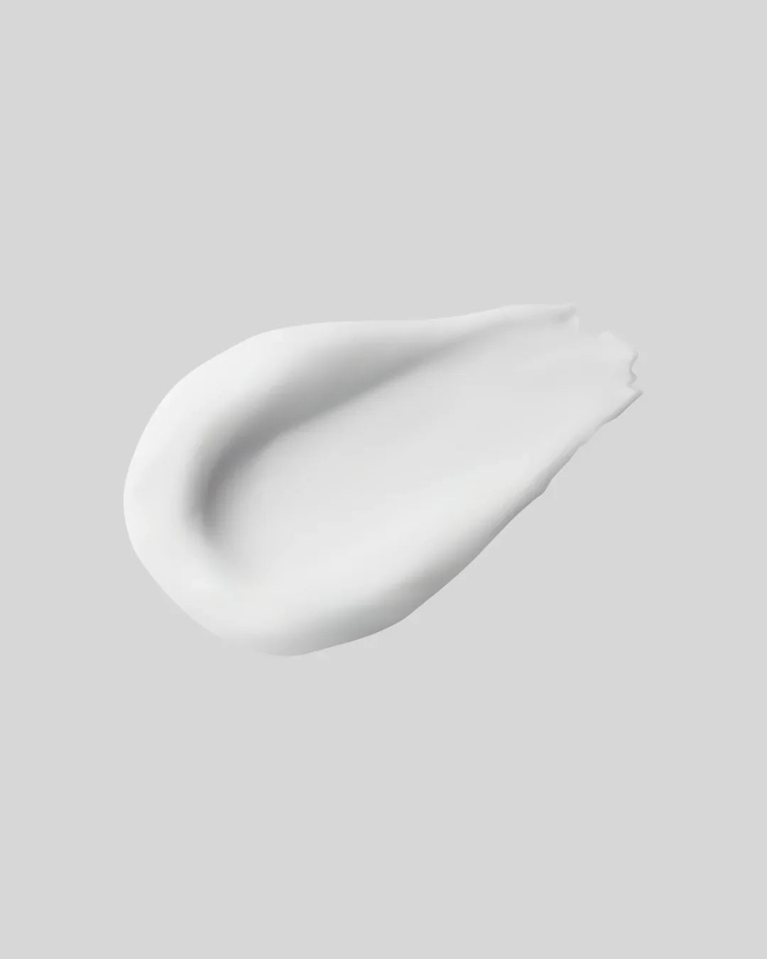 Crema skincare bianca stesa su fondo grigio, BuzzSkin idratazione e luminosità viso