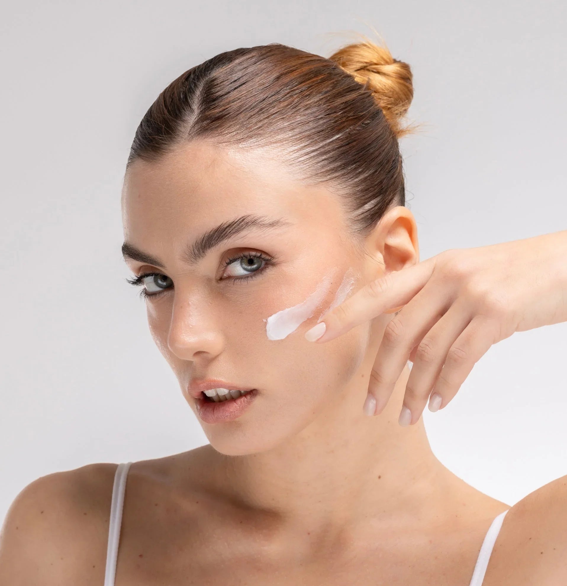 Donna applica crema viso idratante sulla guancia, skincare BuzzSkin per pelle luminosa